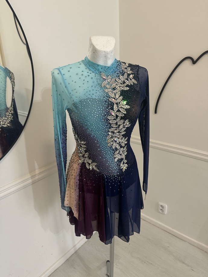 Krasobruslařské kostýmy bývají pružnější než ty taneční a mívají jednodušší, průhlednější sukně. Typické pro ně bývají i barevné stínované přechody jako na tomto modelu pro jinou krasobruslařku