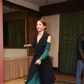 Její smaragdové šaty odhalovaly ramena.