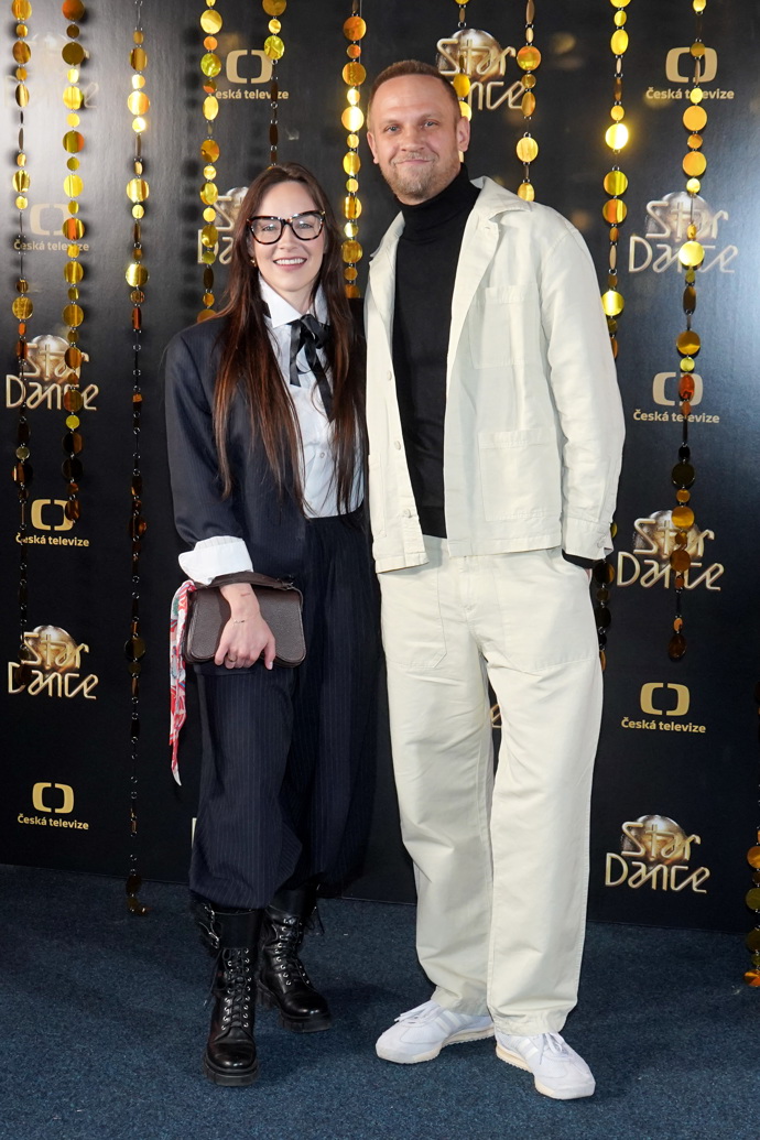 Tomáš Polák a Adriana Mašková. Adriana oblékla bílou košili s černou vázankou, černý kalhotový kostýmek a výrazné těžké boty. 