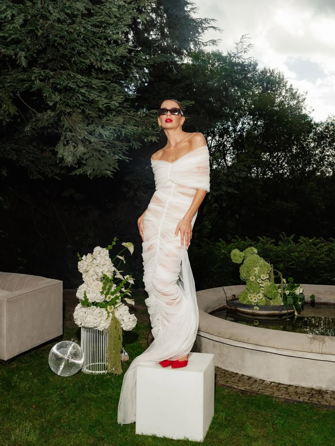 Šaty jsou z tylu, jsou velmi přiléhavé a zdobí je nápadné řasení.