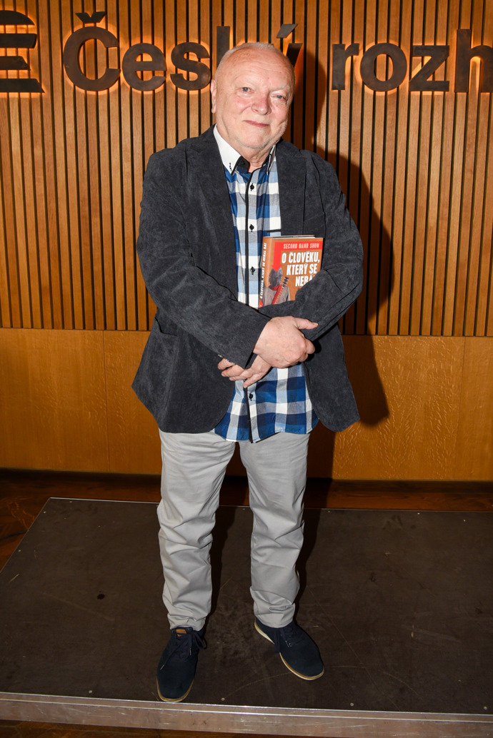 Spisovatel Jan Krůta, jehož kniha se křtila, oblékl tmavě šedé sako, kostkovanou košili a světle šedé kalhoty. 