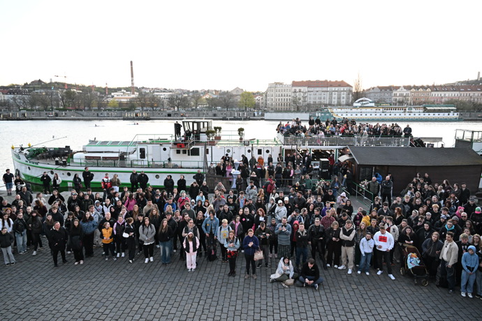 Smutný pohled na zástupy lidí u břehu Vltavy.