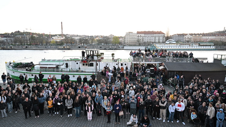 Smutný pohled na zástupy lidí u břehu Vltavy.