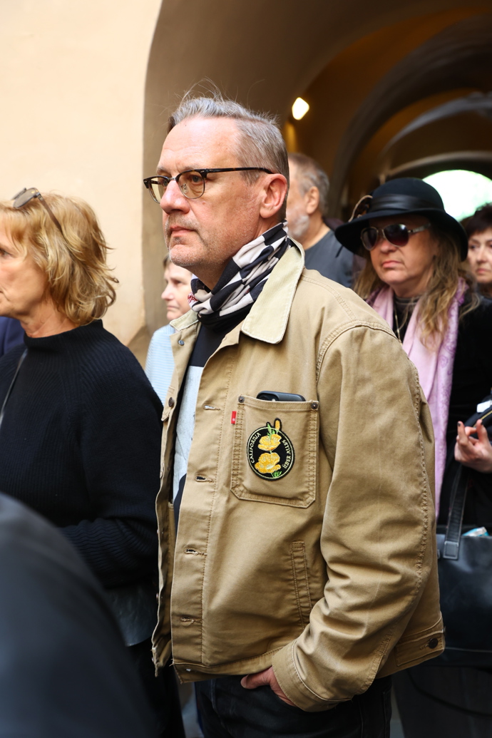 Oproti ostatním hostům měl ležerní bundu.