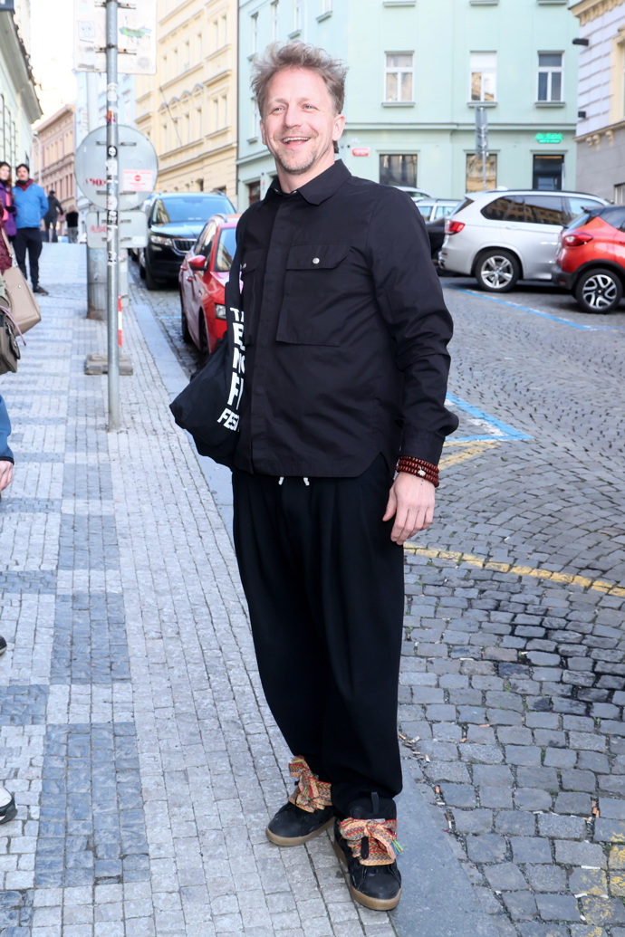 Kombinaci černé a hnědé nosí s oblibou také zpěvák Tomáš Klus, jeho outfitu ale nechybí nápadité detaily v podobě potisku tašky a nezvykle širokých tkaniček u tenisek.