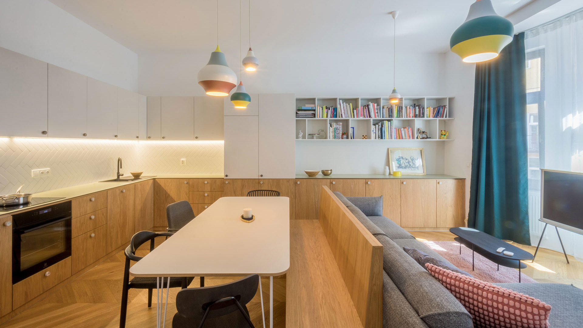Projekt "Různé tváře růžové" v Benešově, navržený architektem Michalem Rouhou z ateliéru Momentura, představuje interiér založený na jednoduchosti a střídmosti. Dominantním materiálem je dub, použitý na podlaze i nábytku, doplněný bílými prvky a jemnými barevnými akcenty. 
