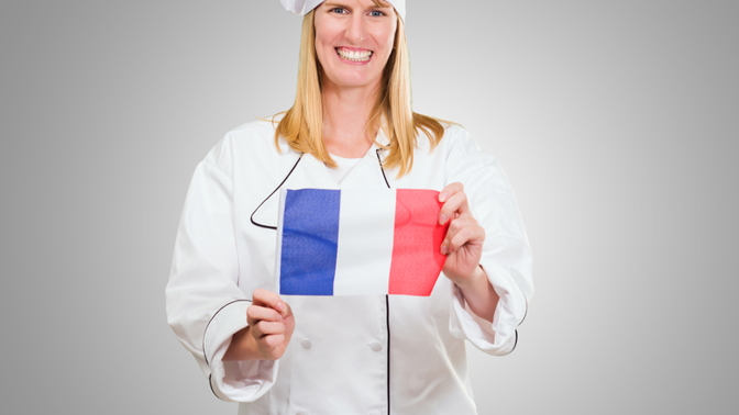 Veselá kuchařka držící francouzskou vlajku