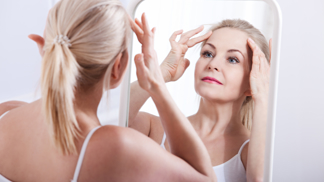 žena 40+ před zrcadlem si prohlíží své vrásky