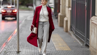 Žena jdoucí po ulici v červeném kabátu. Právě syté barvy jsou trendem roku 2025
