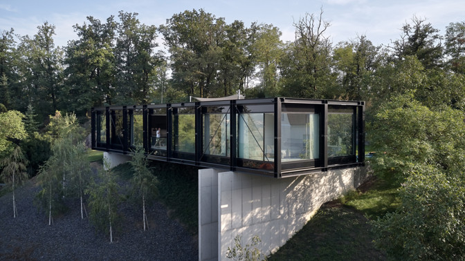 V malebné vilové čtvrti nad Berounkou vyrostla moderní vila Sidonius, která redefinuje pojetí luxusního bydlení. Postavená na prudkém svahu pomocí ocelové mostní konstrukce, nabízí obyvatelům nejen výhledy na krásy Českého krasu a Prahu, ale také originální architektonické a technologické řešení.
