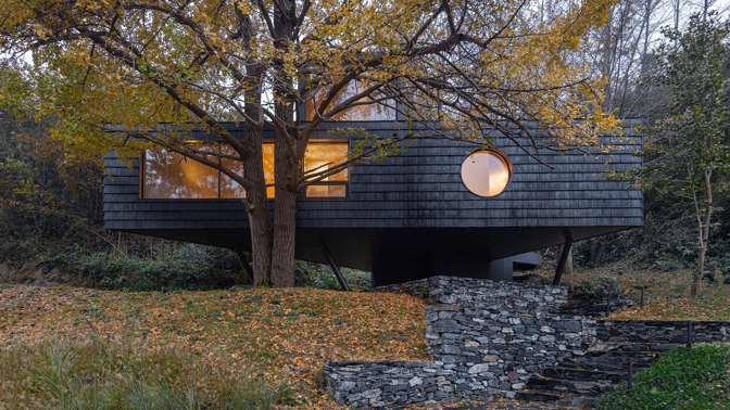 Architekti z Moguang Studio postavili mezi stromy chatu, která neruší, ale přirozeně splyne s lesem. Dům stojí na pilířích, aby nepoškodil kořeny starých stromů, a místo klasických oken má geometrické výřezy, které rámují krajinu.
