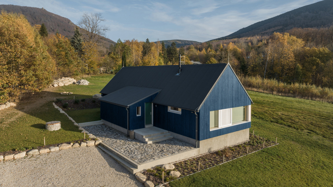 Modrý šindelový obklad a elegantní bílé rámy oken vytvářejí kontrast, který nemůžete přehlédnout. Architektka Markéta Cajthamlová a její tým se postarali o každý detail, ať už jde o interiér plný dřeva nebo promyšlenou dispozici, která nabídne vše, co potřebujete.
