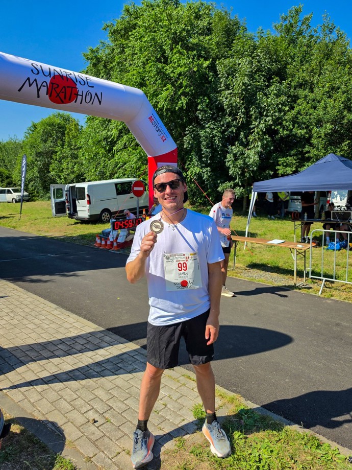 Pavel Callta s medailí pod cílovou bránou Sunrise Marathonu, který startoval už před pátou ráno.