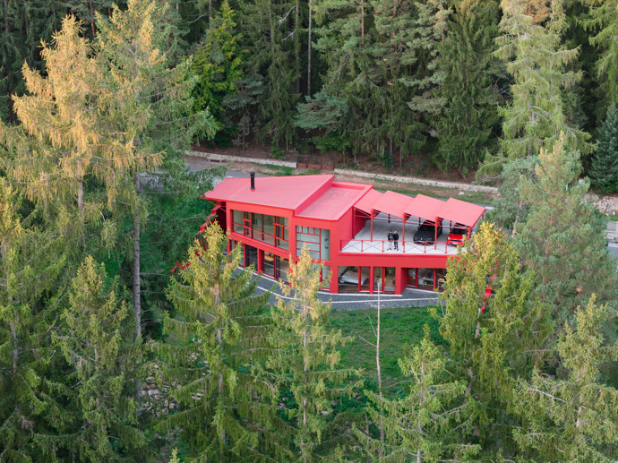 Vila v Jevanech jde přesně opačnou cestou. Architekti z ateliéru Architektura ji oblékli do výrazně červené fasády, která je mezi zelenými korunami stromů nepřehlédnutelná. 
