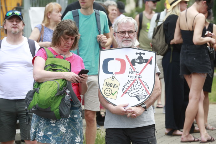 Účastník protestu drží štít s grafikou varující před tím, aby politici utáhli České televizi finanční kohoutky.