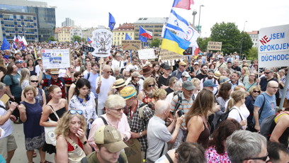 FOTO: Pohled do zaplněného davu demonstrantů nesoucích různé transparenty a státní vlajky.