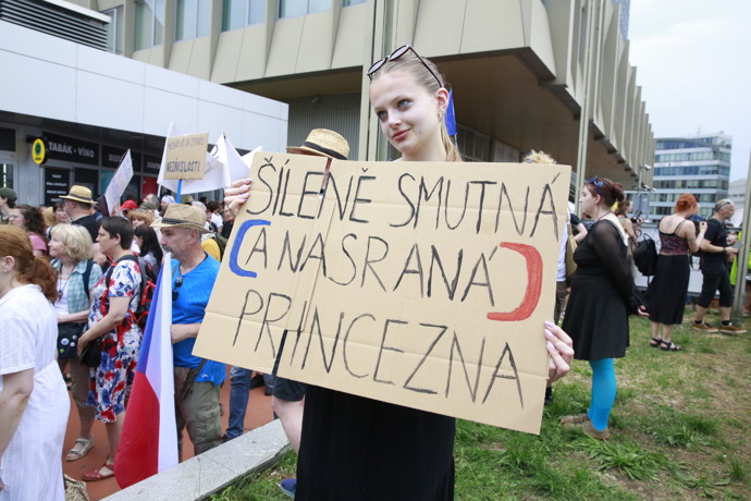Mladá dívka vyjadřuje svůj nesouhlas s politickou situací pomocí ručně psaného kartonu.