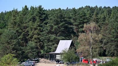 FOTO: Pohled z dálky na hlavní rezidenci s výraznou strmou střechou, u níž stojí zaparkovaná auta a panuje čilý ruch.