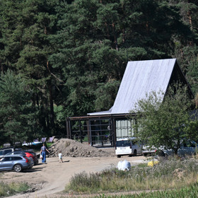 Uprostřed přírody vyrůstá nepřehlédnutelná moderní prosklená stavba.