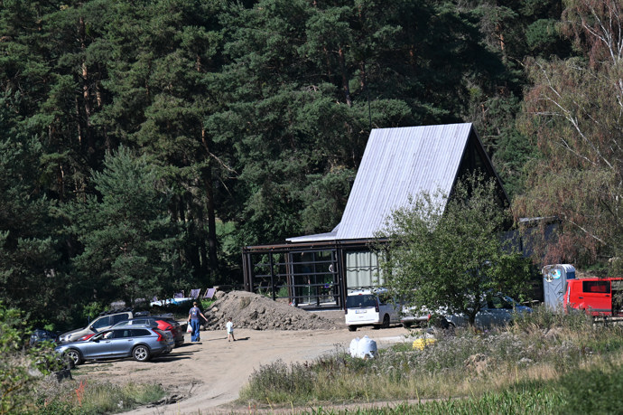 Uprostřed přírody vyrůstá nepřehlédnutelná moderní prosklená stavba.