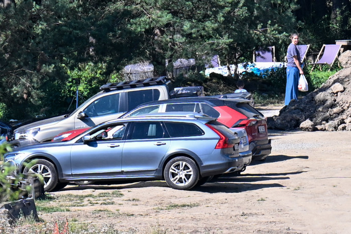 Radana s taškou sledovala dění na pozemku, kde parkuje i několik rodinných vozů.