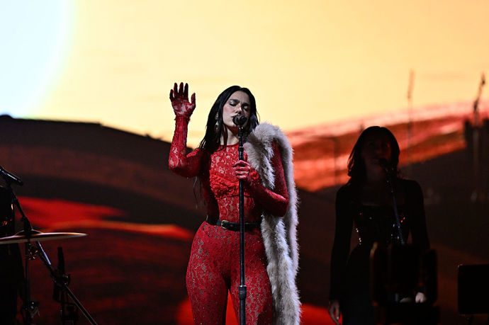 Dua Lipa na svém turné Radical Optimism v roce 2025 často oblékala overaly, které jí na míru vytvořil Alessandro Michelle, kreativní ředitel značky Valentino