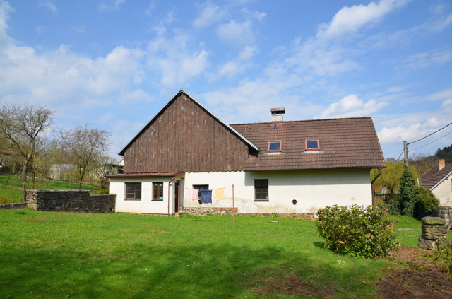 Obyčejný venkovský domek se stodolou proměnili architekti v moderní stavbu s opalovanou fasádou. Na chalupu sem jezdí tři generace jedné rodiny  