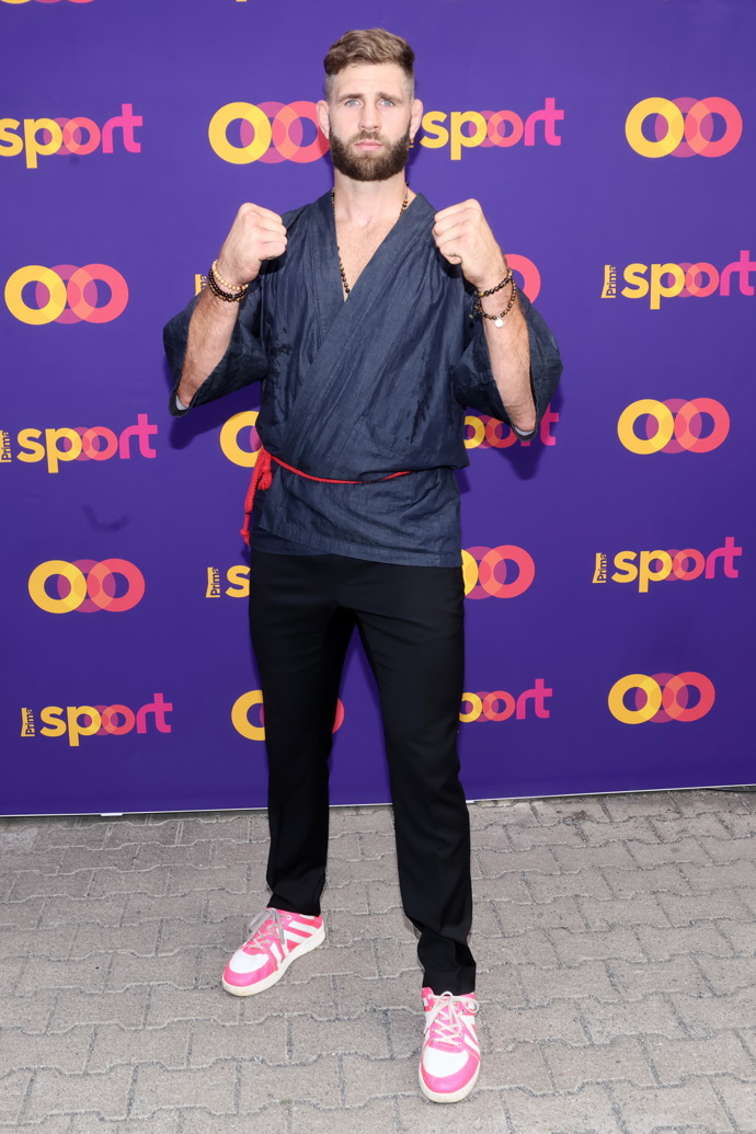 Jiří Procházka oblékl tmavě modrou asijskou halenu s červeným páskem, outfit doplnil zářivými barevnými teniskami. 