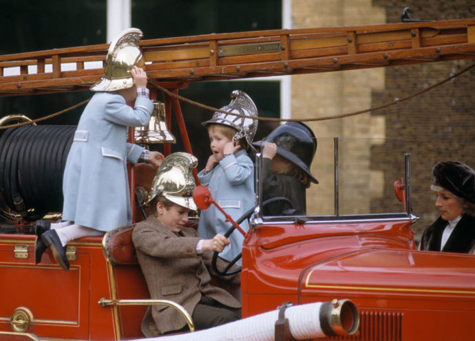  (zleva) Jeho královská Výsost princ William, bratranec Peter Phillips, Jeho královská Výsost princ Harry a sestřenice Zara Phillips hrají na hasičském voze Merryweather z roku 1939 s princeznou Dianou (vpravo vzadu) v muzeu Sandringham na panství Sandringham v Norfolku 3. ledna 1988. Princové mají na sobě kabáty navržené Catherine Walker