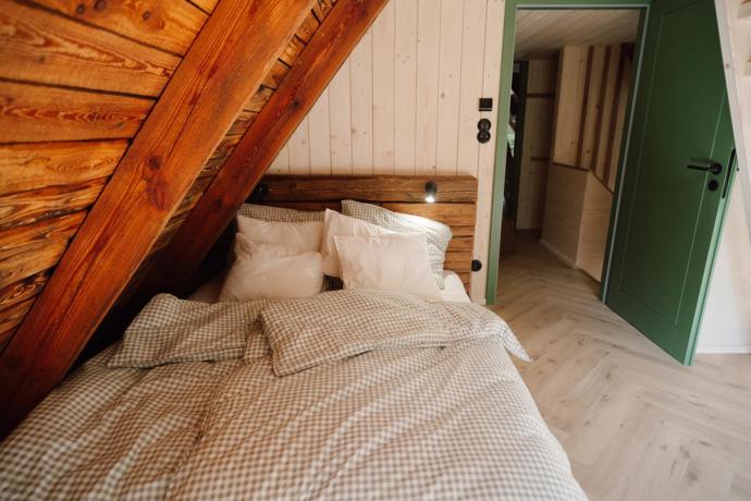 Masivní dřevo v ložnici kontrastuje se světlými stěnami a zelenými dveřmi Masivní dřevo v ložnici kontrastuje se světlými stěnami a zelenými dveřmi