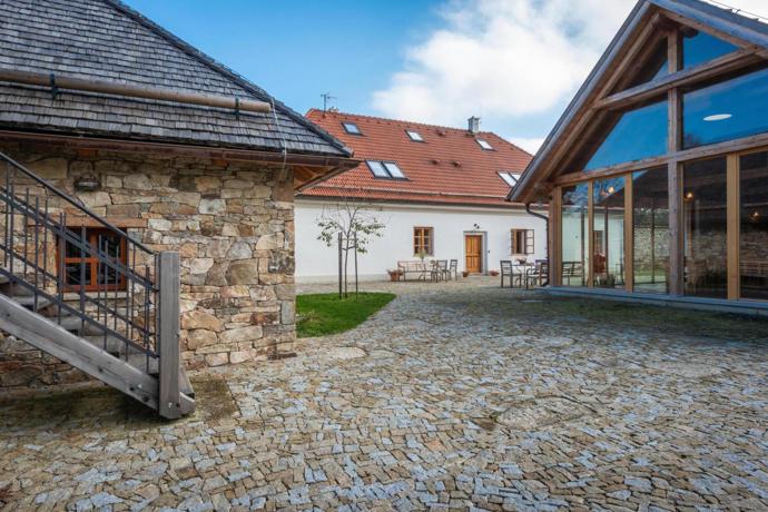 Uzavřený dvůr propojuje hlavní bílou budovu s kamenným objektem a prosklenou stodolou, která do tradičního areálu přináší lehčí současný prvek
