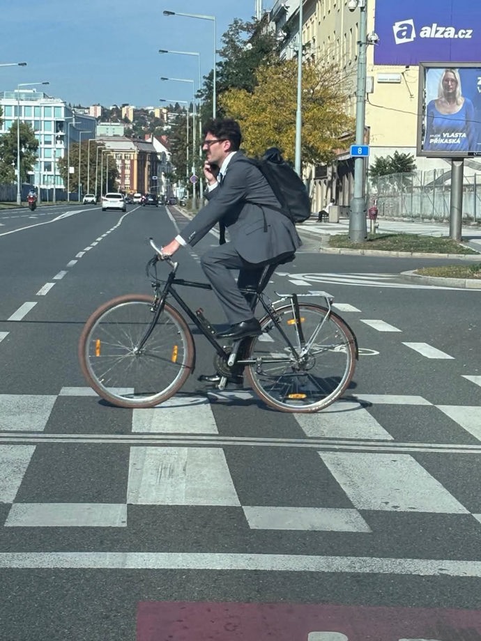 Adam Scheinherr telefonuje a jede na kole přes přechod.