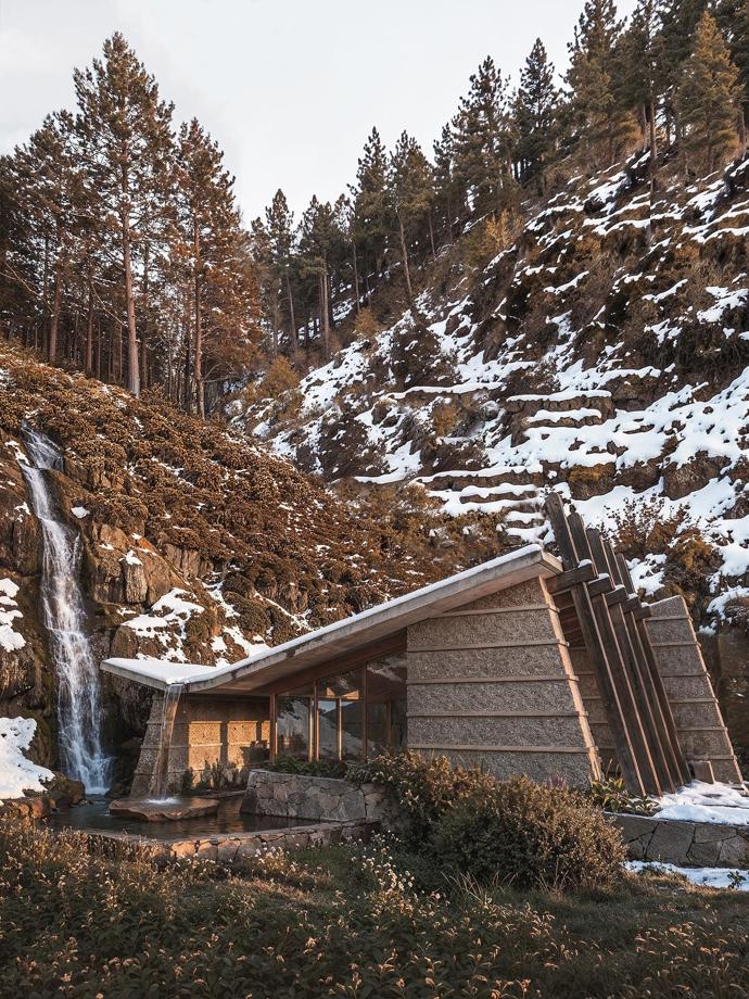 Z větší vzdálenosti je dobře vidět, jak se jednotlivé části domu rozprostírají mezi stromy a nechávají vyniknout horské panorama