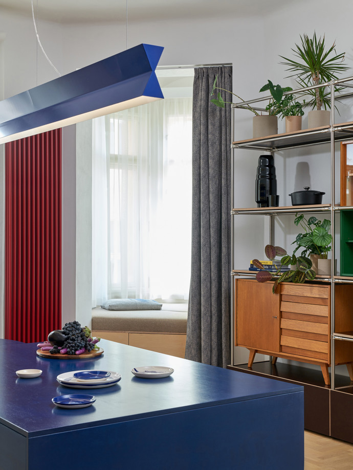 Výrazné modré svítidlo, modrý ostrůvek a červený radiátor ukazují, že se architekti barevných kontrastů rozhodně nebáli Výrazné modré svítidlo, modrý ostrůvek a červený radiátor ukazují, že se architekti barevných kontrastů rozhodně nebáli