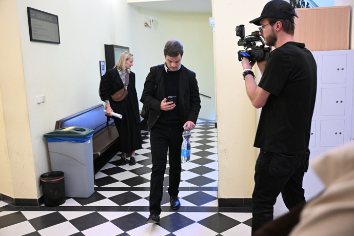 Adam Kraus přichází k soudu začtený do mobilu.